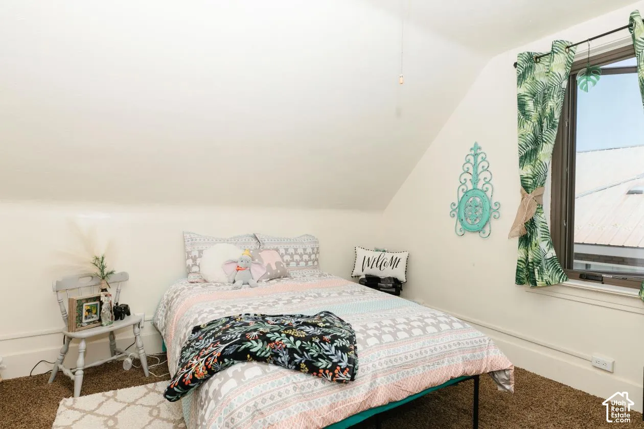Carpeted bedroom featuring lofted ceiling and baseboards