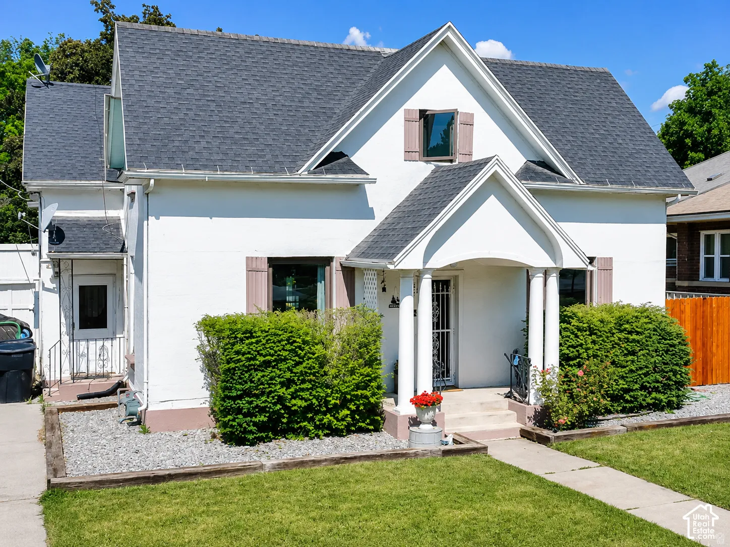 White exterior with contrasting dark shingle roof and decorative shutters