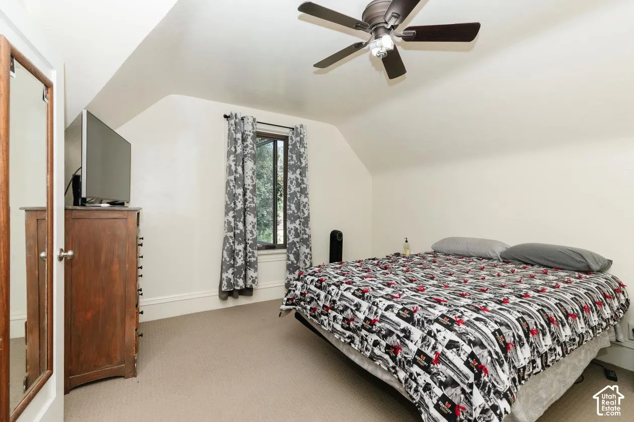 Bedroom featuring vaulted ceiling, light colored carpet, and a ceiling fan