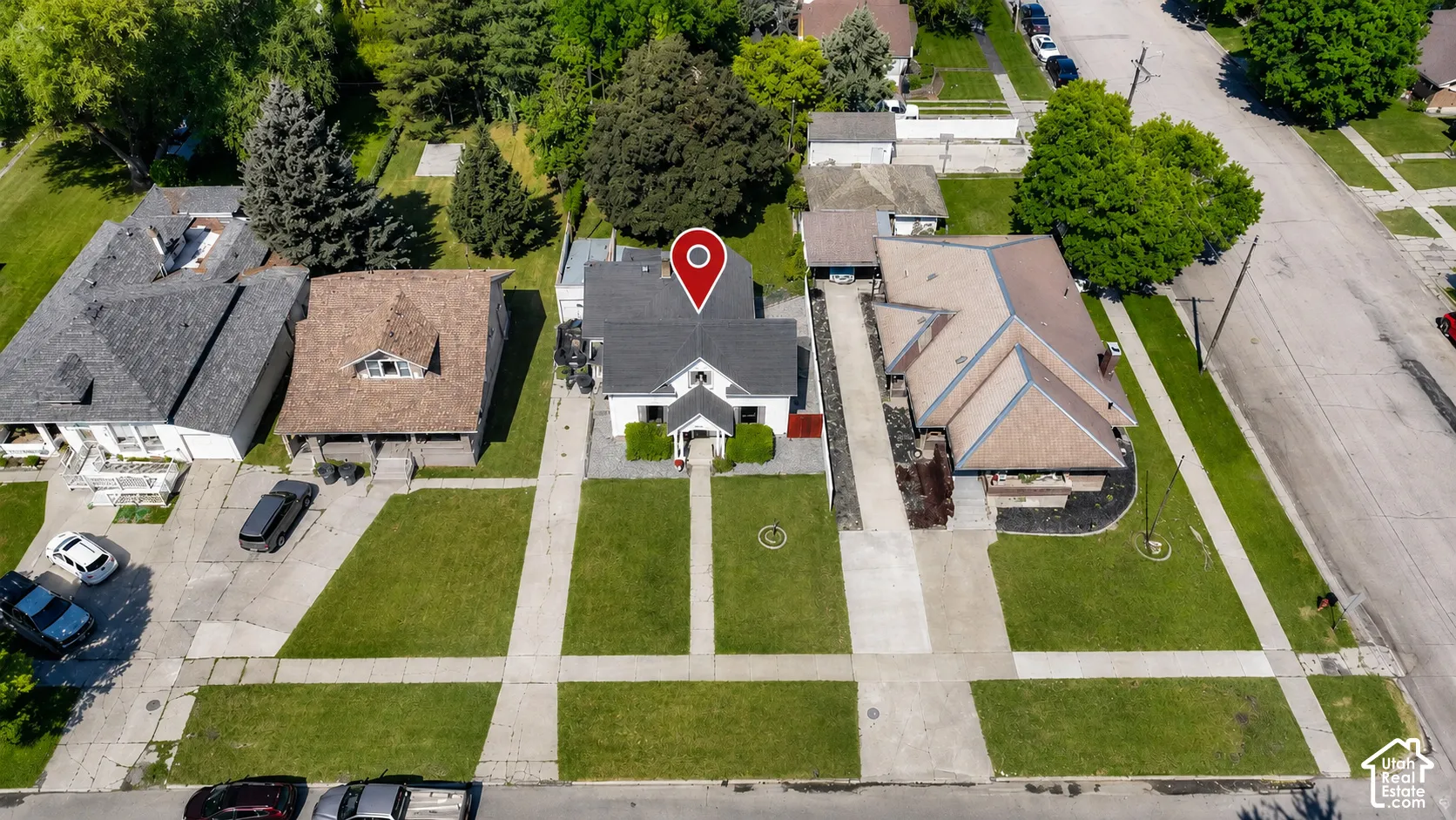 Aerial perspective showcasing the property with a white exterior, dark roof, and a prominent front entrance