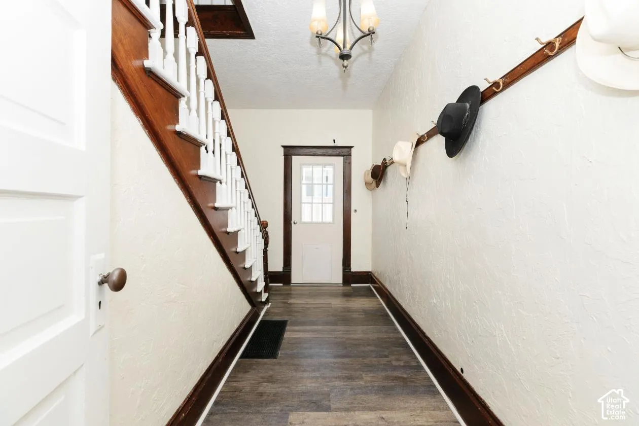 Entryway with a textured wall, a textured ceiling, wood finished floors, and a chandelier