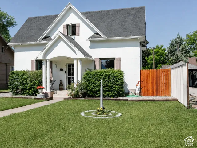 White exterior residence featuring a prominent gabled roofline and an inviting covered porch with decorative columns
