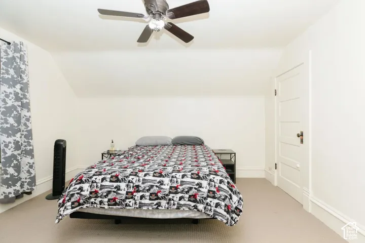 Bedroom with vaulted ceiling, light colored carpet, and ceiling fan