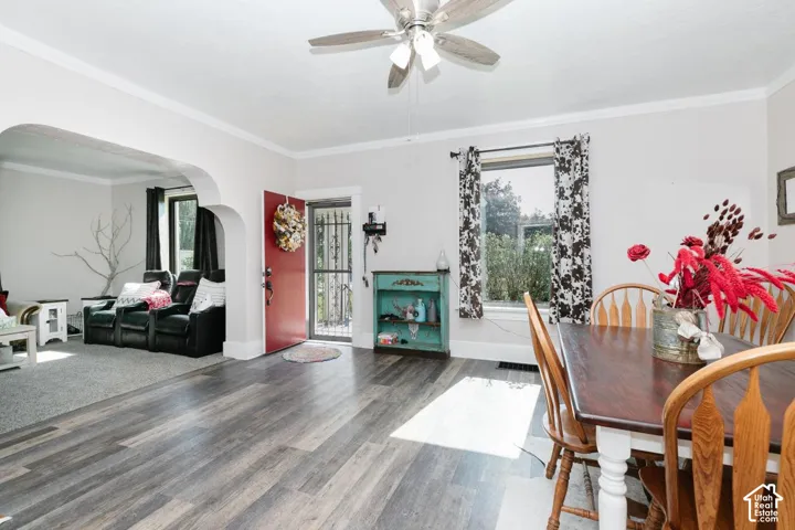 Dining area with wood finished floors, a ceiling fan, crown molding, and arched walkways
