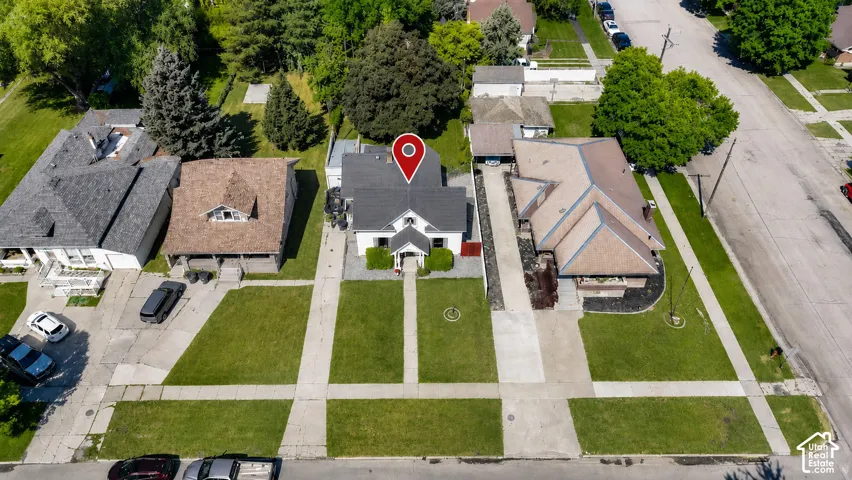 Aerial perspective showcasing the property with a white exterior, dark roof, and a prominent front entrance