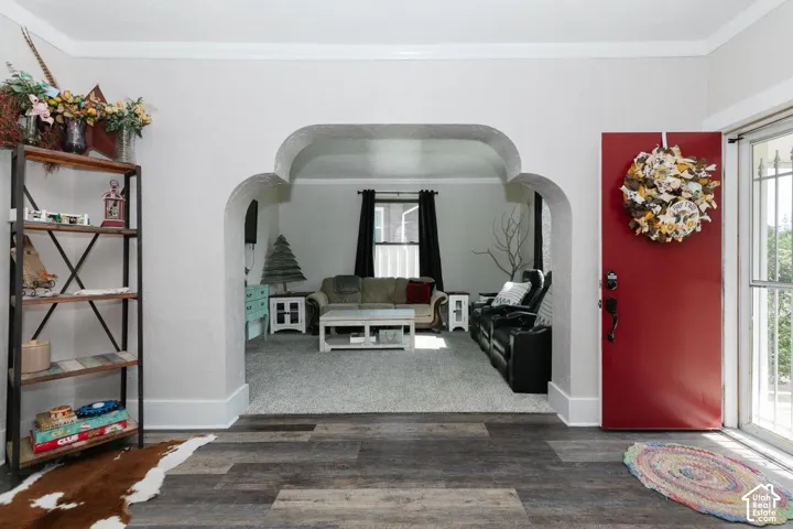 Entryway featuring wood finished floors, crown molding, and arched walkways