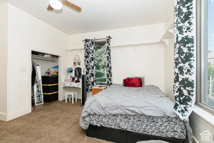 Carpeted bedroom featuring a closet and a ceiling fan and there is a washer and dryer hookup in the closet