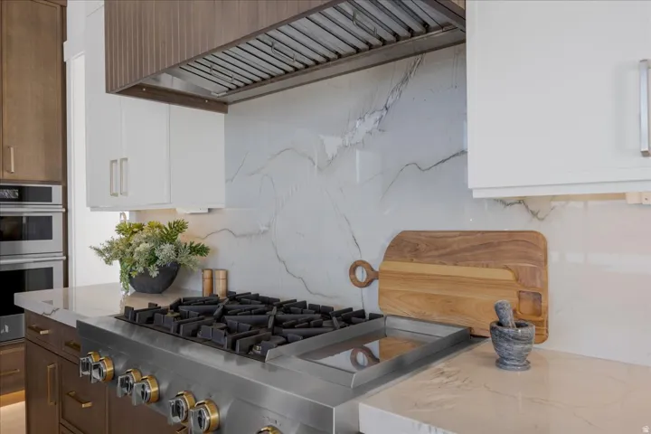 Dual tone kitchen with dual tone cabinetry, stainless steel appliances, and light stone counters