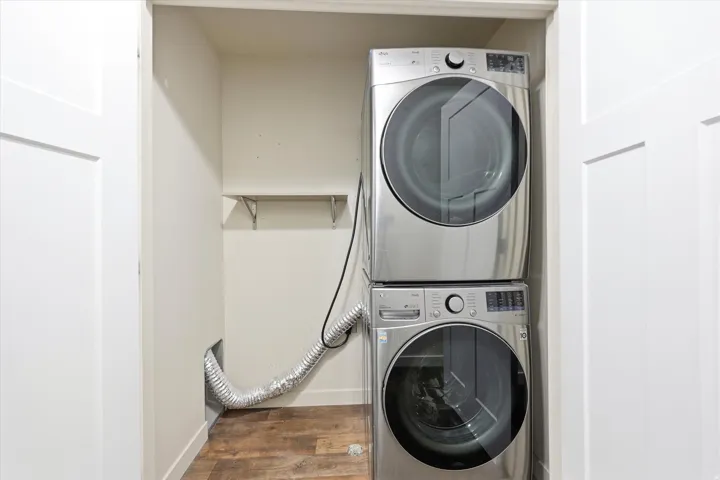 Closet with wood-finish flooring, white walls, built-in shelving, and bifold doors