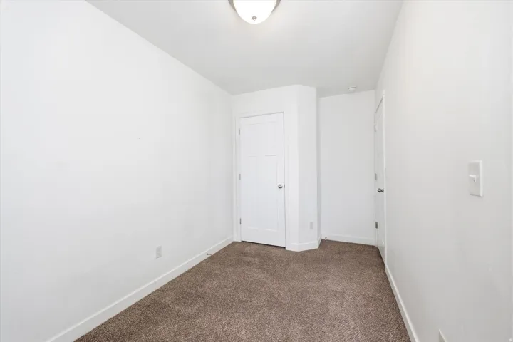 Neutral color palette with textured carpeting, white baseboards, and a semi-flush mount ceiling light fixture