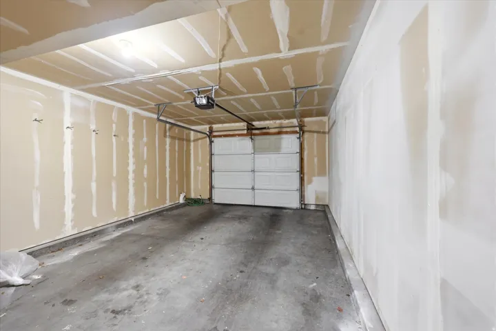 Attached garage with a concrete floor, an overhead garage door, and visible ceiling joists