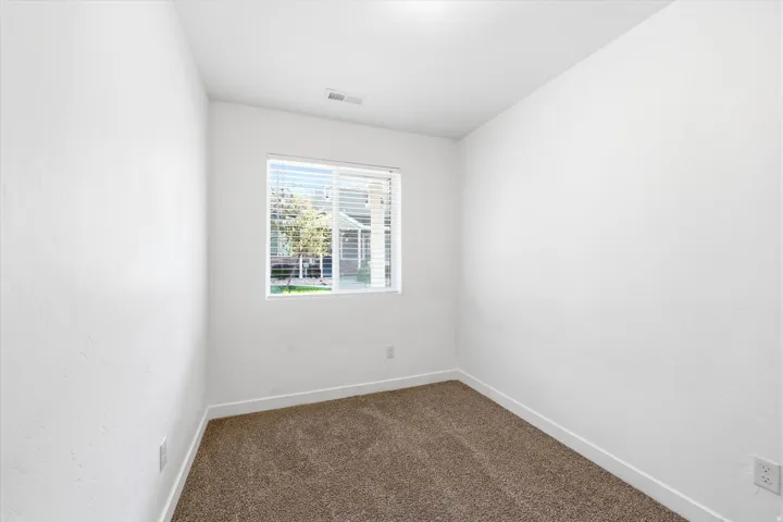 Carpeted flooring, white walls, and a window with blinds