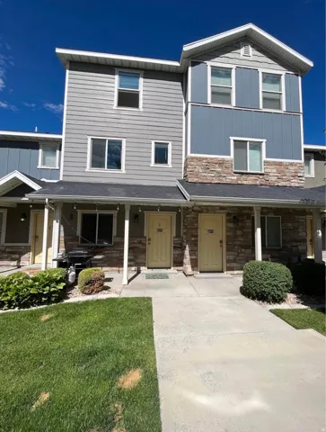View of front facade with a porch, stone siding, board and batten siding, and a front yard