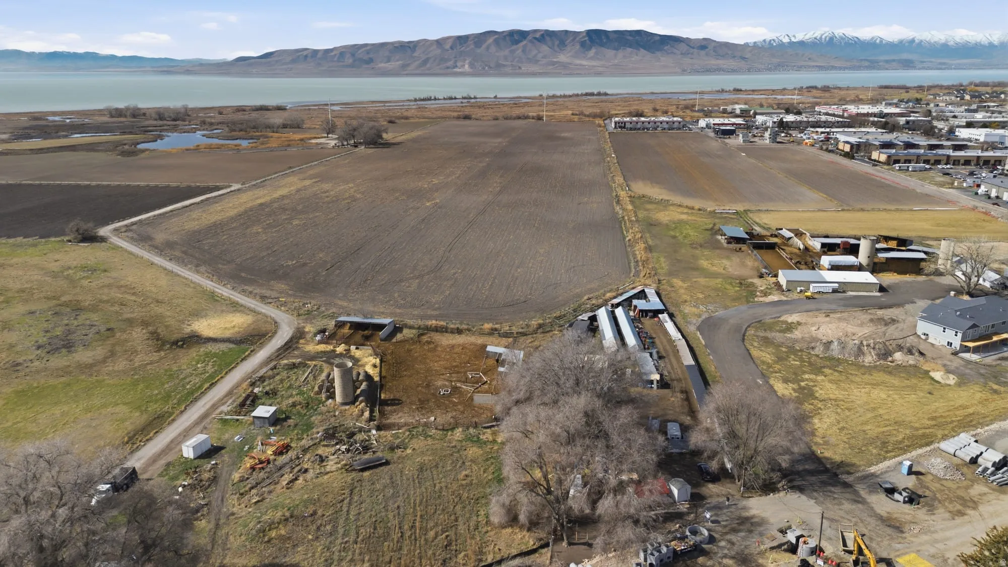 Aerial view of property and surrounding area featuring rural landscape, a water and mountain view, and extensive farmland