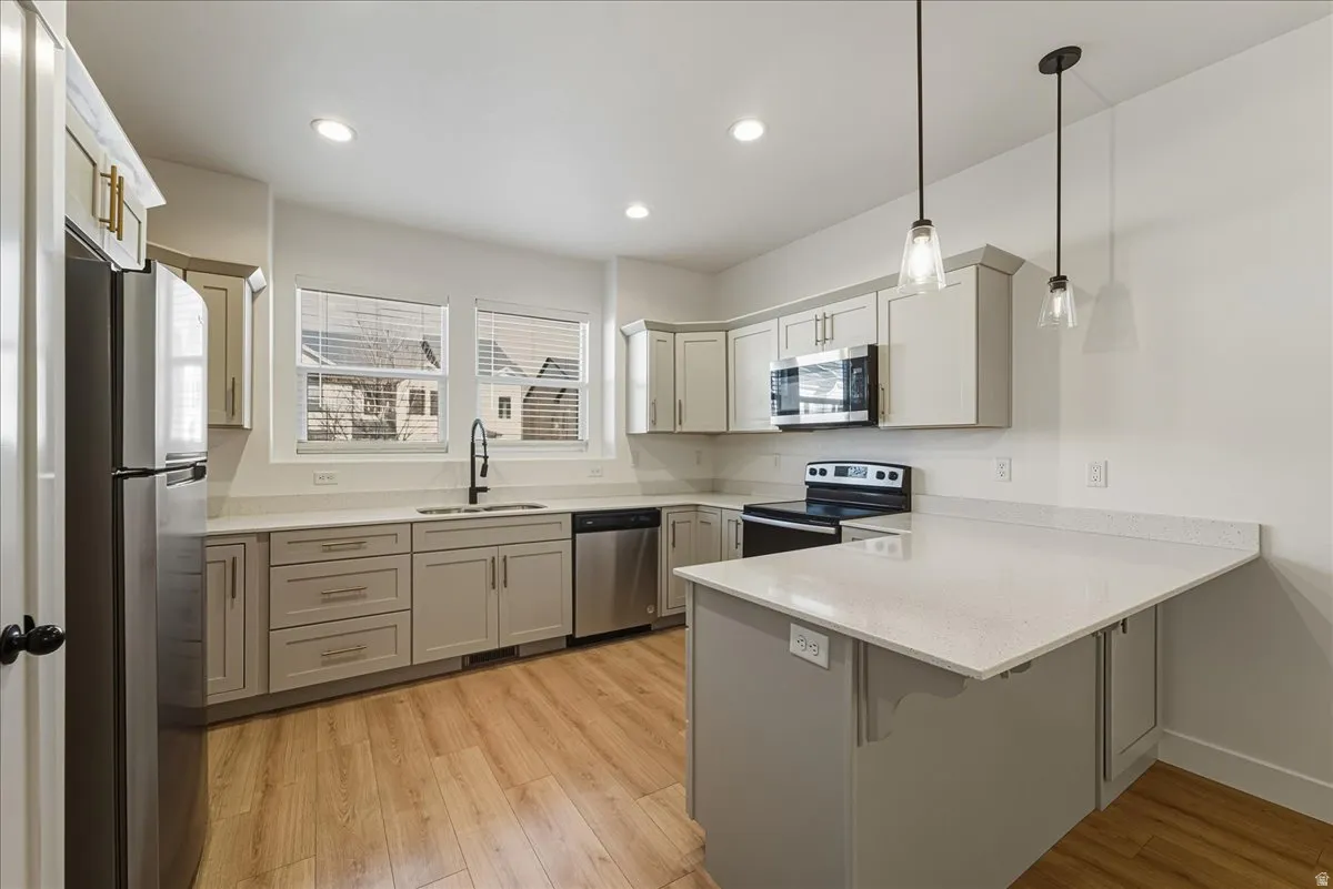 Kitchen with a peninsula, stainless steel appliances, light wood-style flooring, and a breakfast bar area