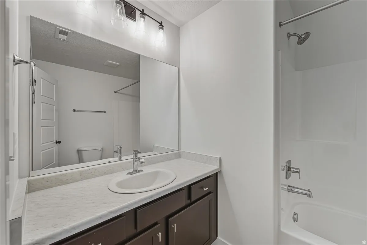 Full bathroom with shower / bath combination, vanity, and a textured ceiling