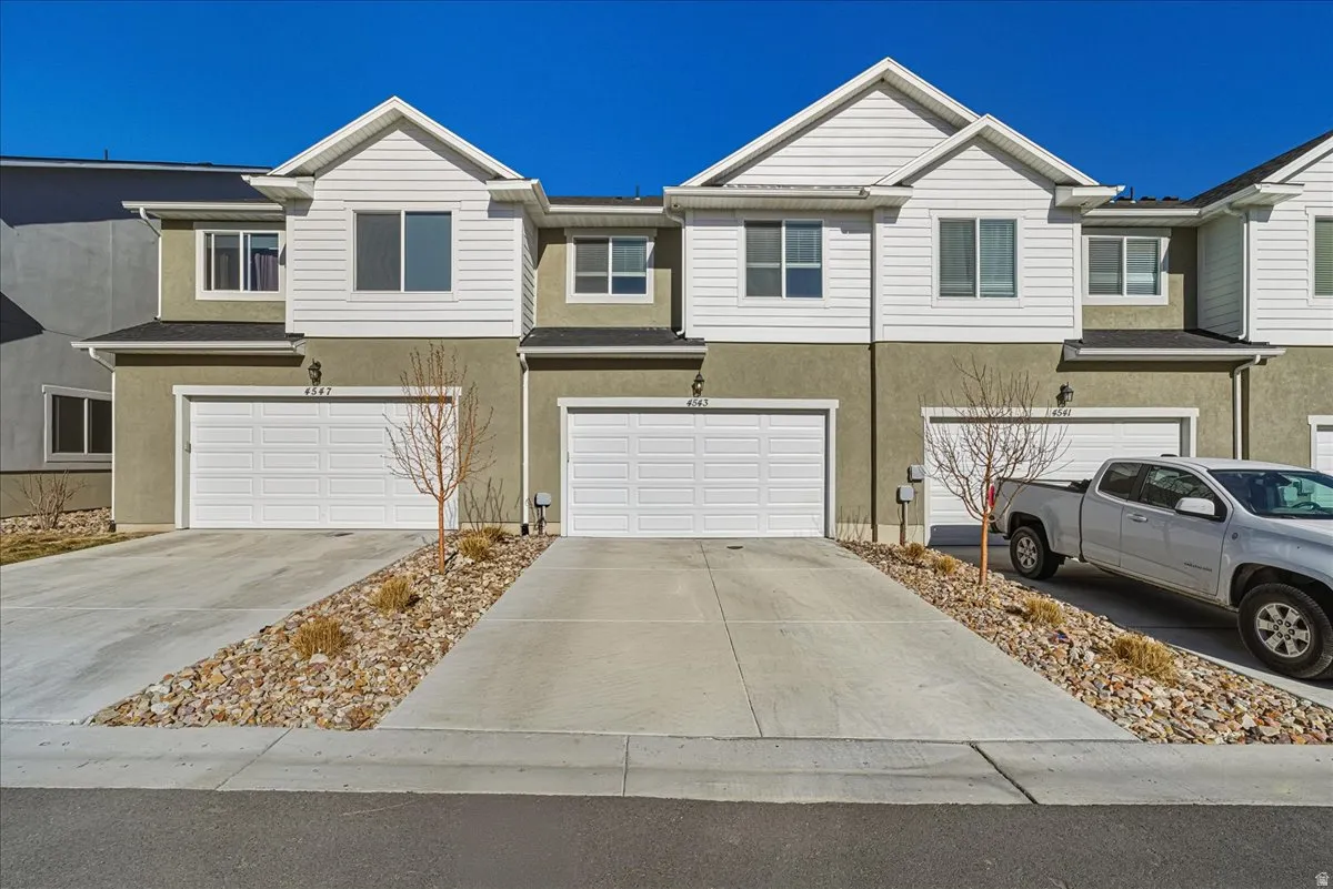 Traditional-style house featuring stucco siding, an attached garage, and concrete driveway