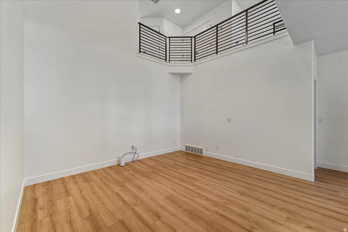 Spare room featuring a high ceiling, light wood-style floors, and recessed lighting