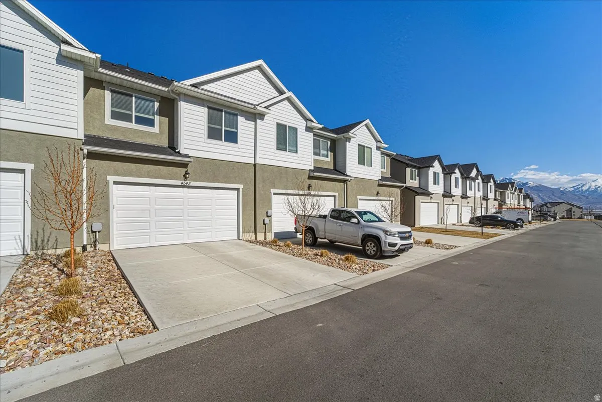 View of front of home featuring a residential view, stucco siding, driveway, and a garage