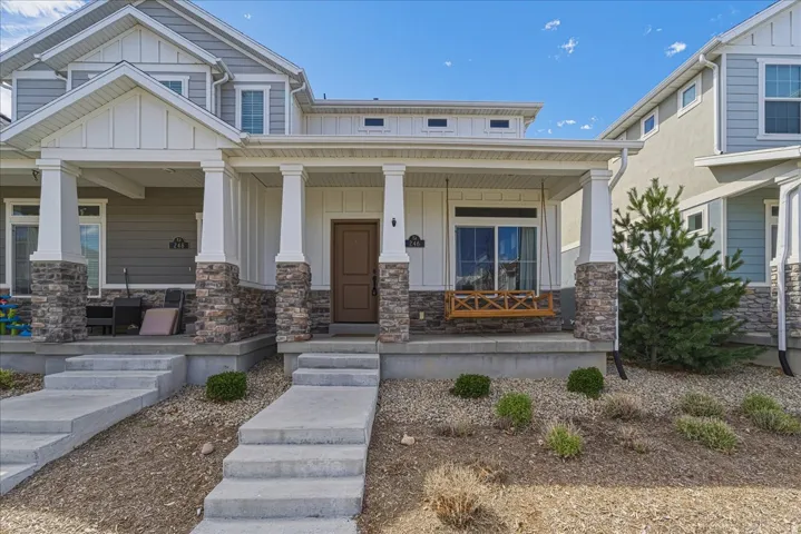 Craftsman-style house featuring board and batten siding, stone siding, and covered porch