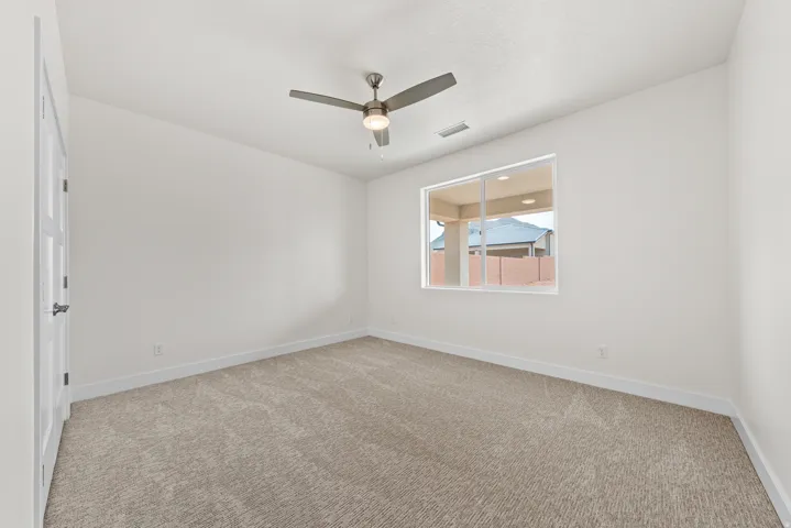 Unfurnished room featuring light carpet and a ceiling fan