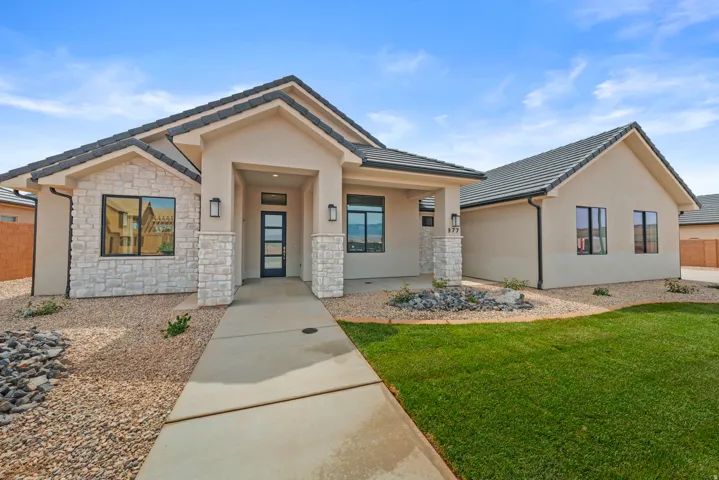 View of front of house featuring stucco siding, stone siding, a front lawn, and a tile roof
