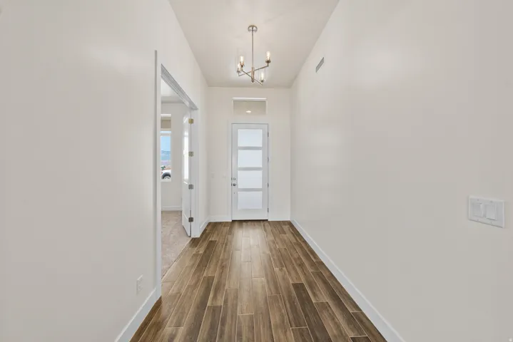 Doorway with wood finished floors and suspended lighting
