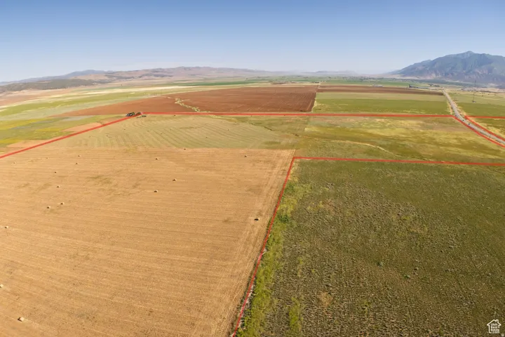 Aerial view of sparsely populated area featuring mountains, property parcel outlined, and farmland