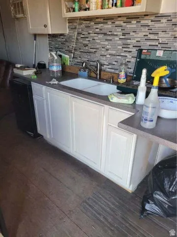 Kitchen with dark wood finished floors, decorative backsplash, open shelves, white cabinets, and dark countertops