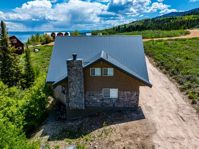 View of side of property featuring a metal roof, stone siding, and a forest view