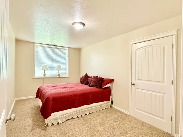 Carpeted bedroom with a textured ceiling and baseboards