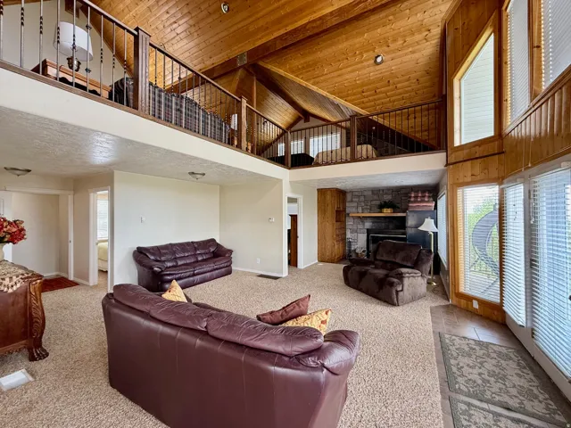 Living area featuring a fireplace, carpet, and a vaulted wood ceiling