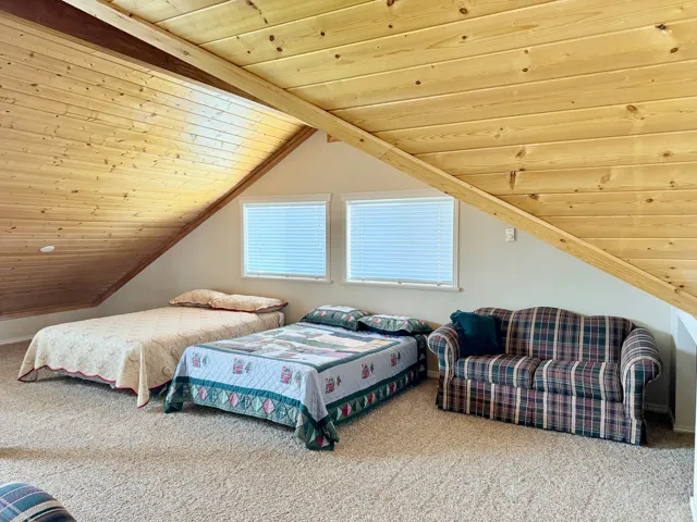 Carpeted bedroom featuring a wood ceiling with exposed beams