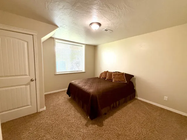 Bedroom with a textured ceiling and carpet floors