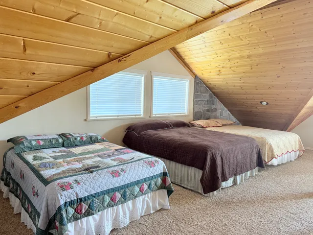 Carpeted bedroom with a vaulted wood ceiling