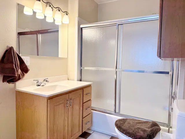 Full bathroom with vanity, enclosed tub / shower combo, and washer / dryer