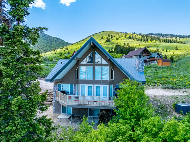 Rear view of property with a deck with mountain view, stone siding, and a metal roof