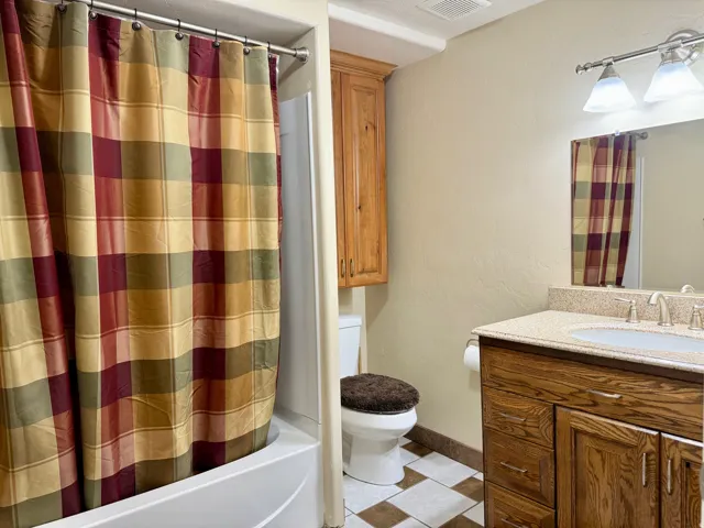 Full bathroom with vanity, a textured wall, tile patterned flooring, and shower / bathtub combination with curtain
