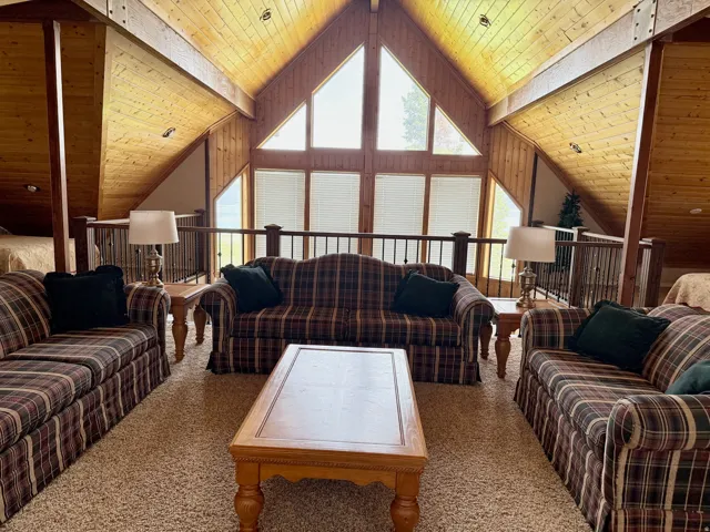 Living room with a wooden ceiling with exposed beams and carpet flooring