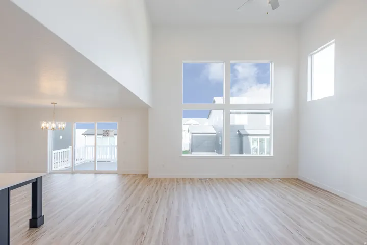 Two-story living area with high ceilings, large multi-pane windows, and light wood-finish flooring