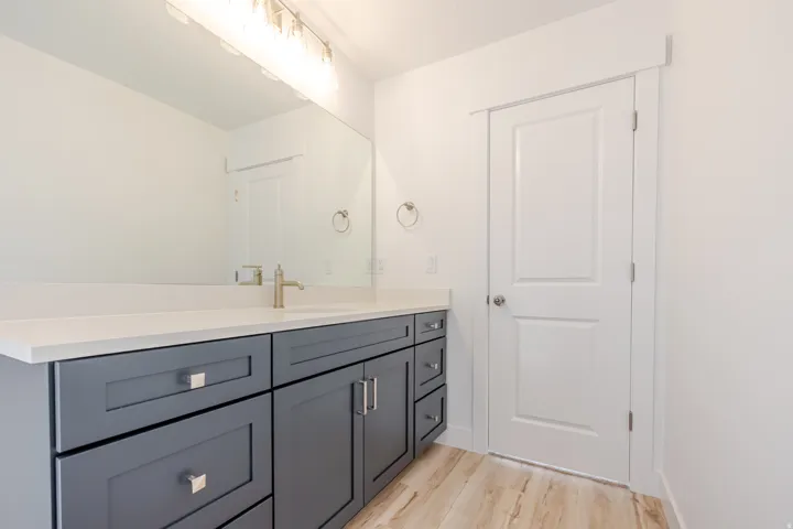 Bathroom vanity featuring a light countertop, dual undermount sink, and brushed gold faucet
