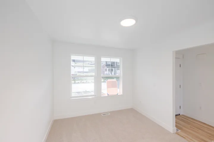 Bright room featuring two large windows, neutral carpeting, a flush-mount ceiling light, and white baseboards