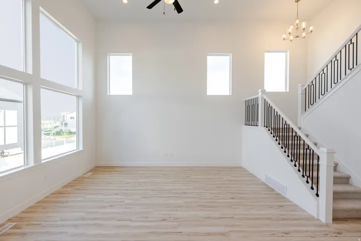 Open-concept living space with wood-finish flooring, soaring ceilings, and a contemporary chandelier