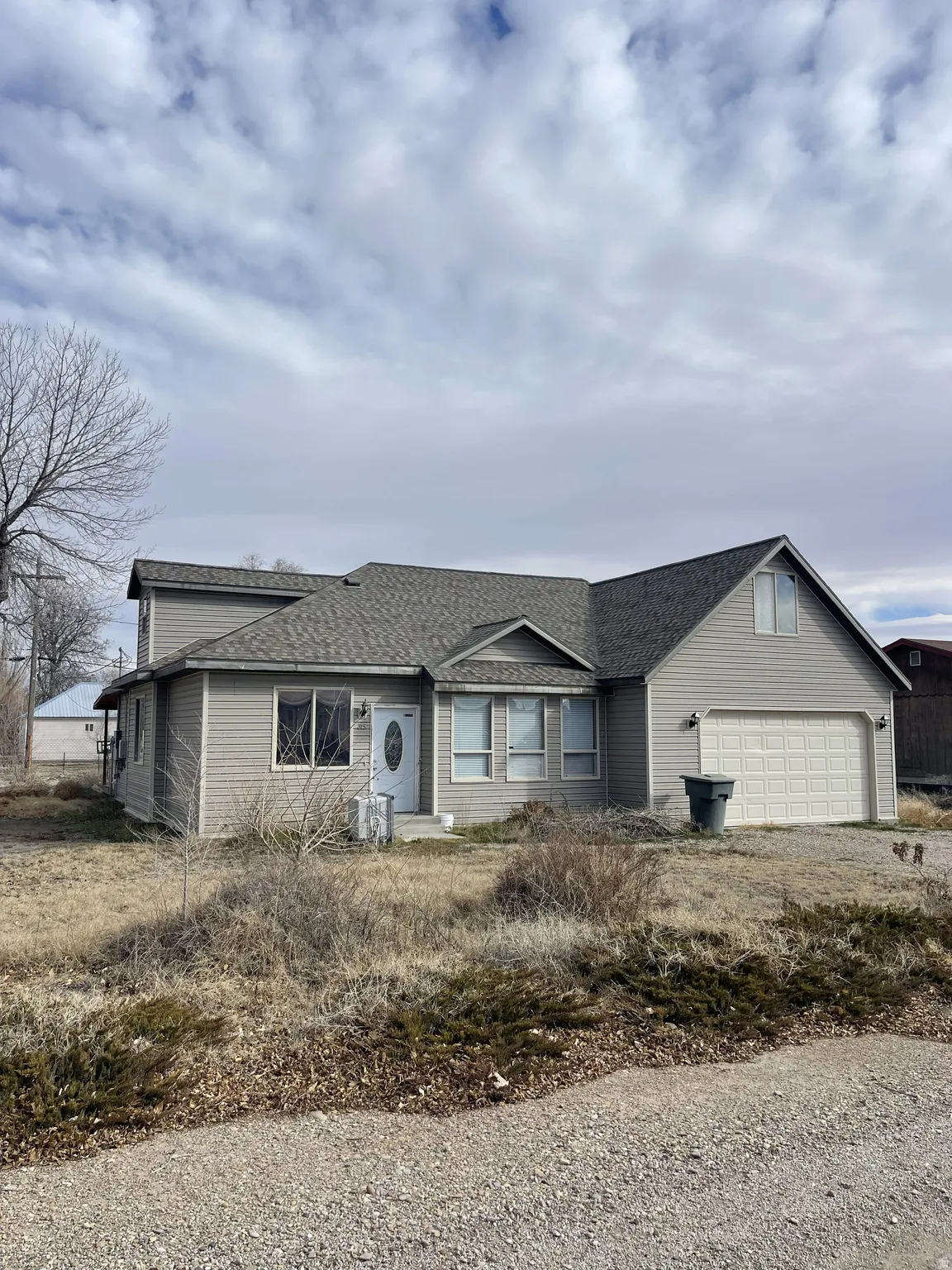 Ranch-style home with roof with shingles, driveway, and an attached garage