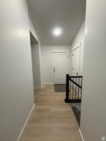 Hall with light wood-type flooring and an upstairs landing