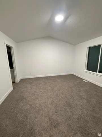 Bonus room featuring baseboards and dark carpet
