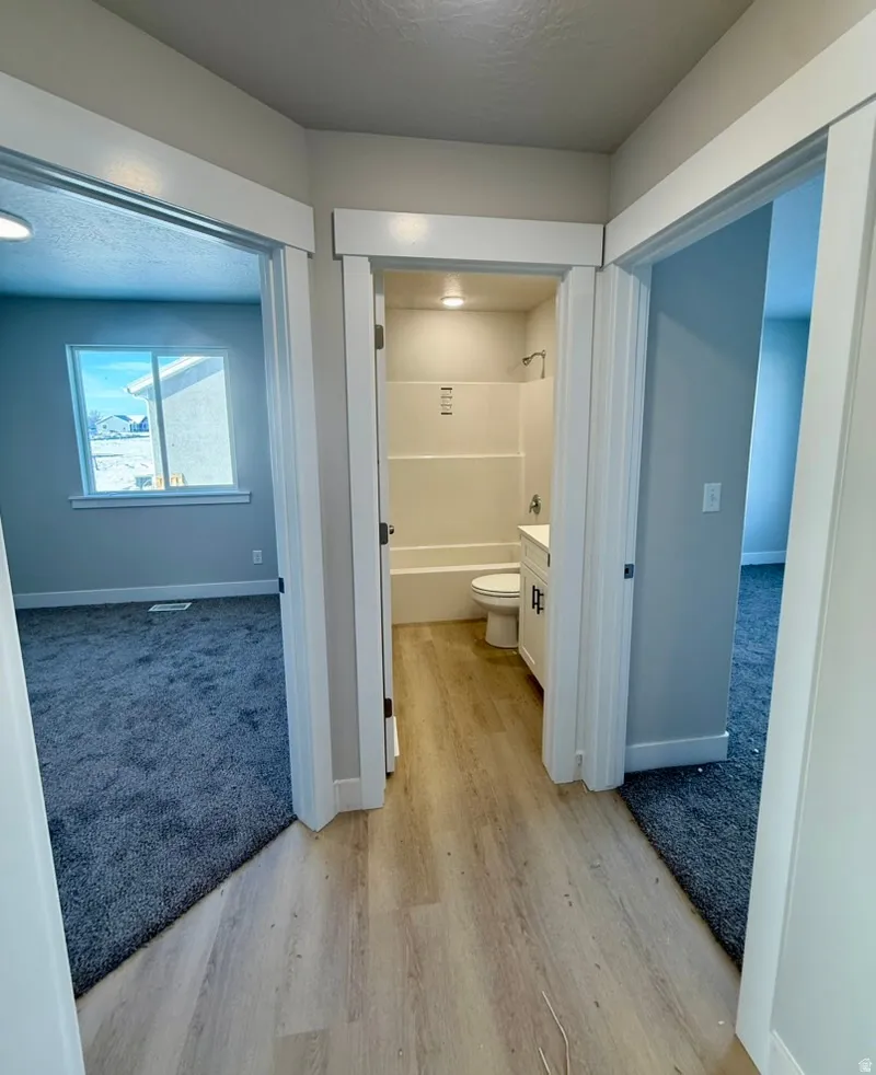 Full bathroom featuring vanity, shower / tub combination, a textured ceiling, light carpet, and light wood-style flooring