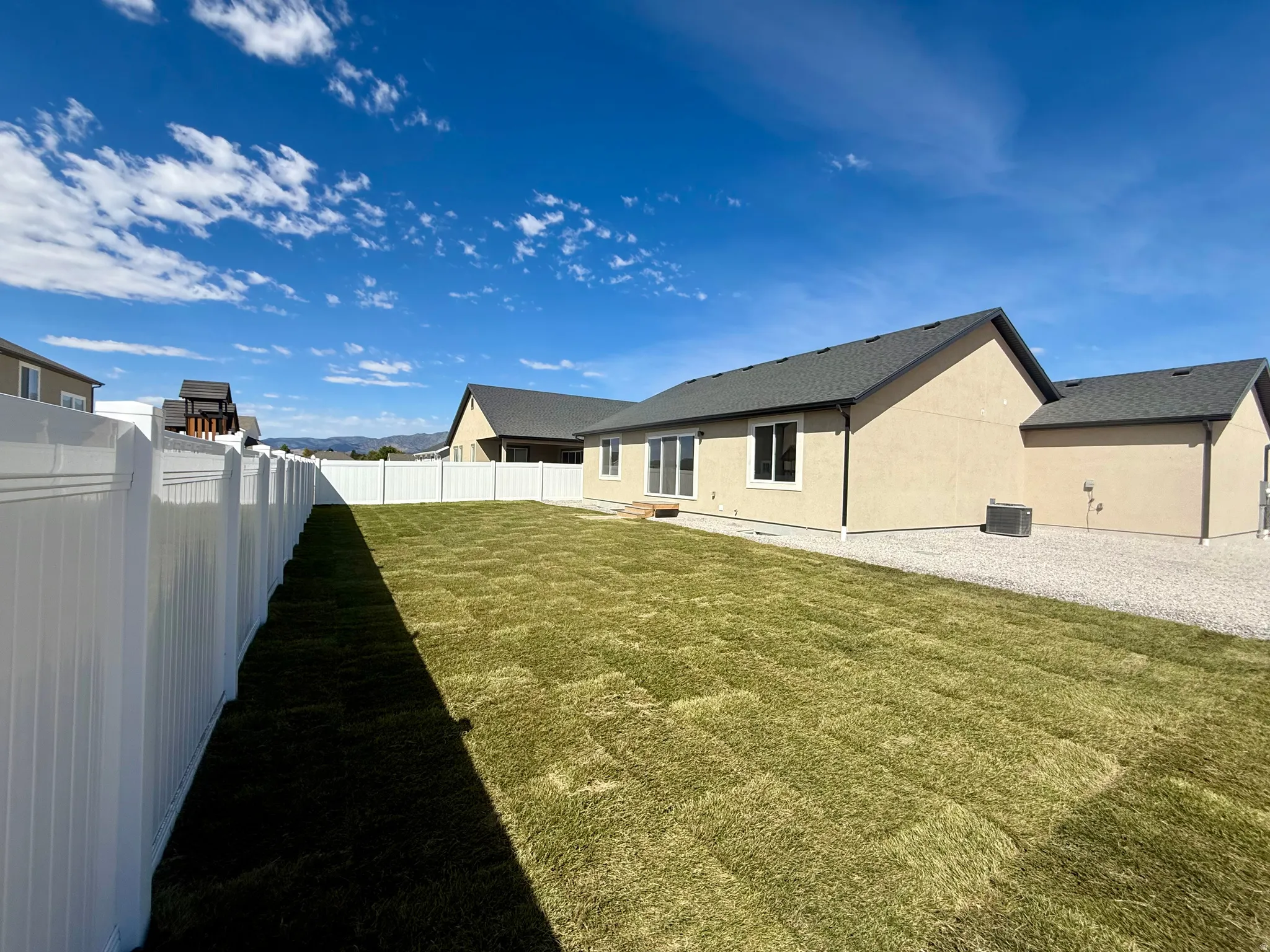 Expansive backyard featuring newly laid sod, a full perimeter privacy fence, and a gravel side yard