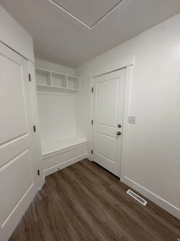LVP, built-in storage bench, recessed shelving, and white paneled doors