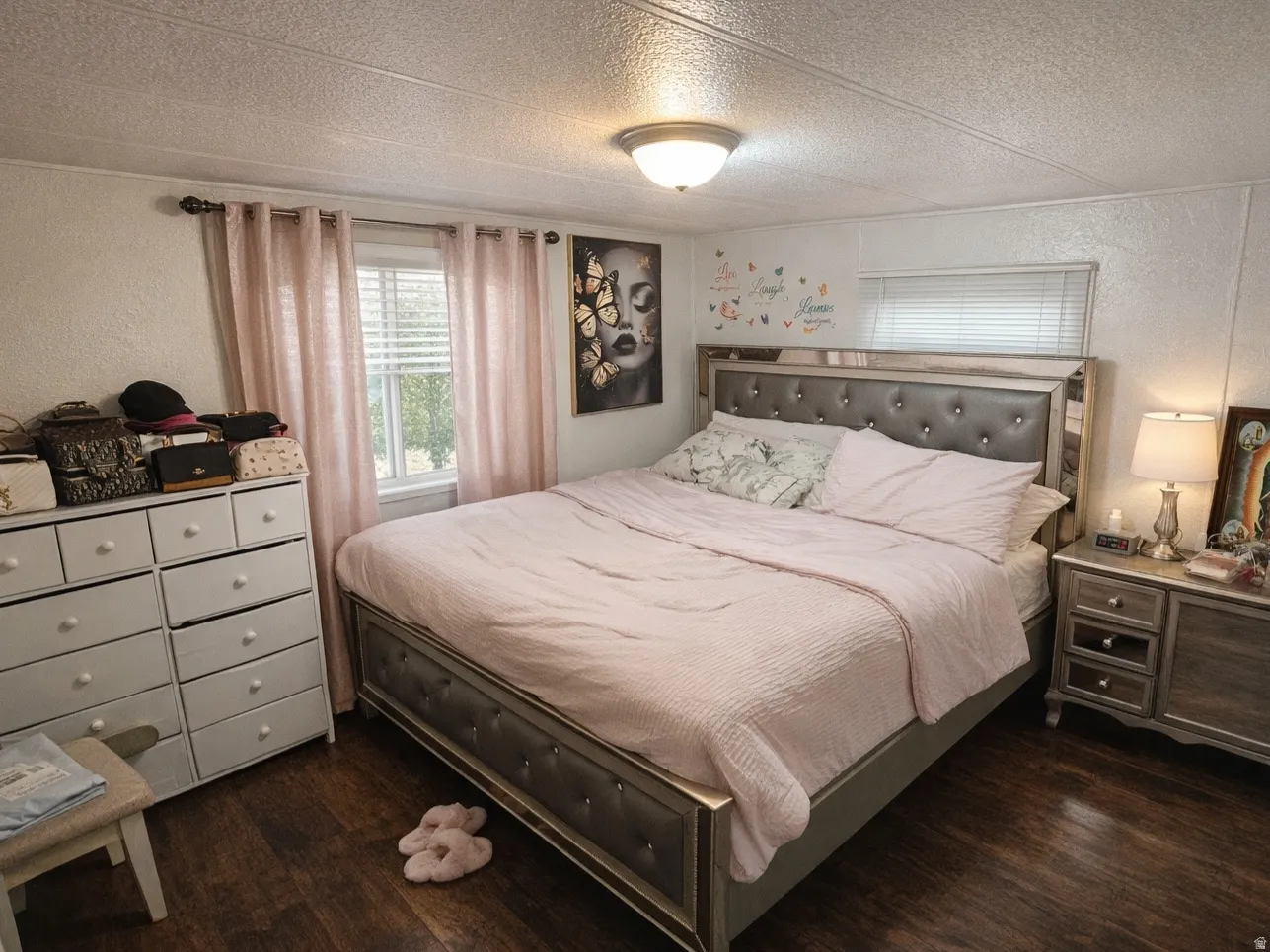 Bedroom with a textured wall, dark wood finished floors, and a textured ceiling